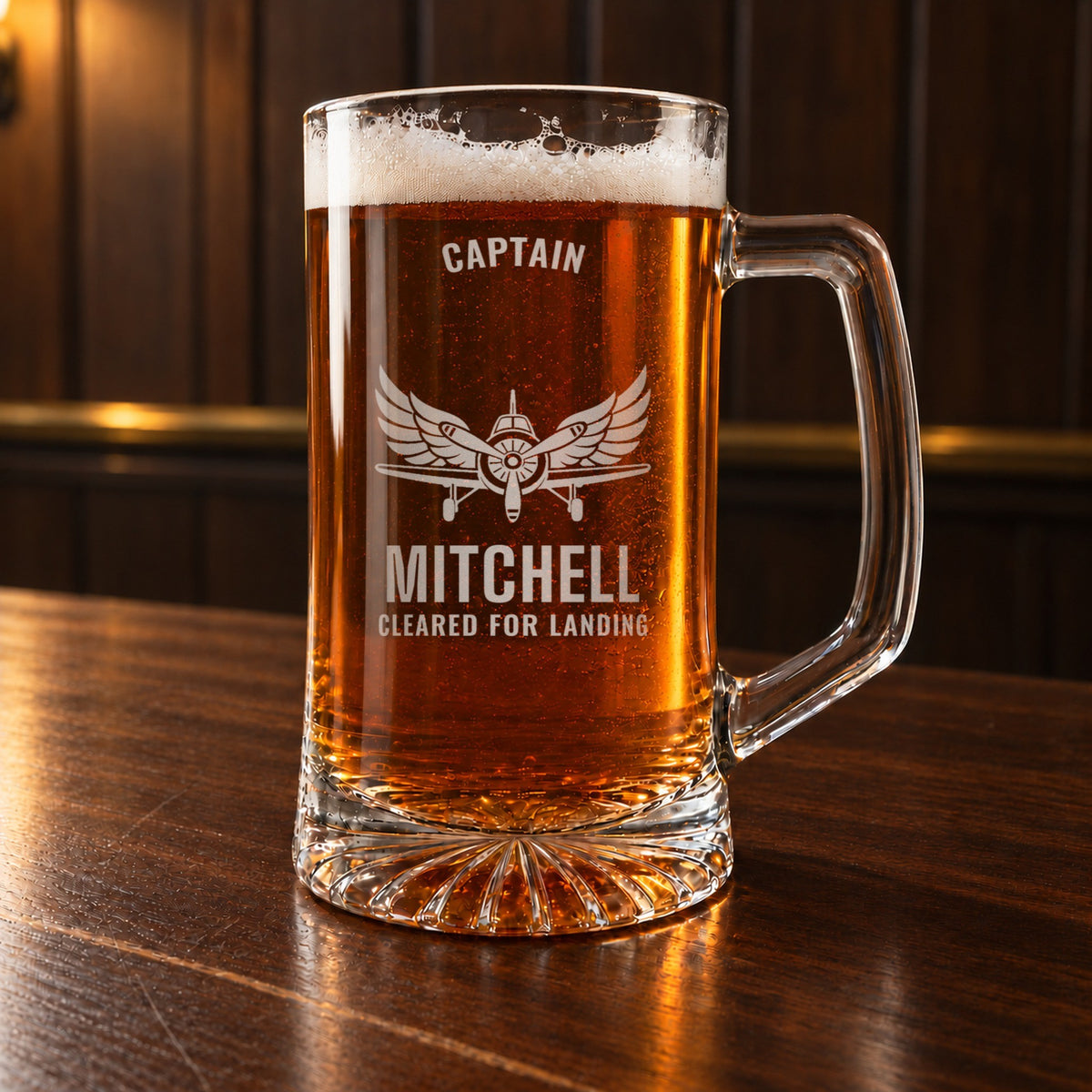 Personalized pilot beer stein on a walnut bar, engraved with a vintage propeller airplane and spread wings: Captain, Mitchell, Cleared for Landing