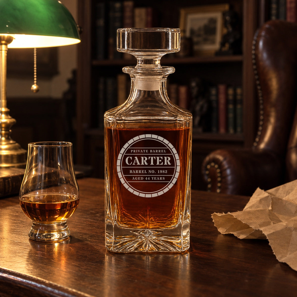 Private Barrel decanter engraved Carter, Barrel No. 1982, on a walnut desk in a study with a tasting glass of bourbon and torn kraft paper beside it