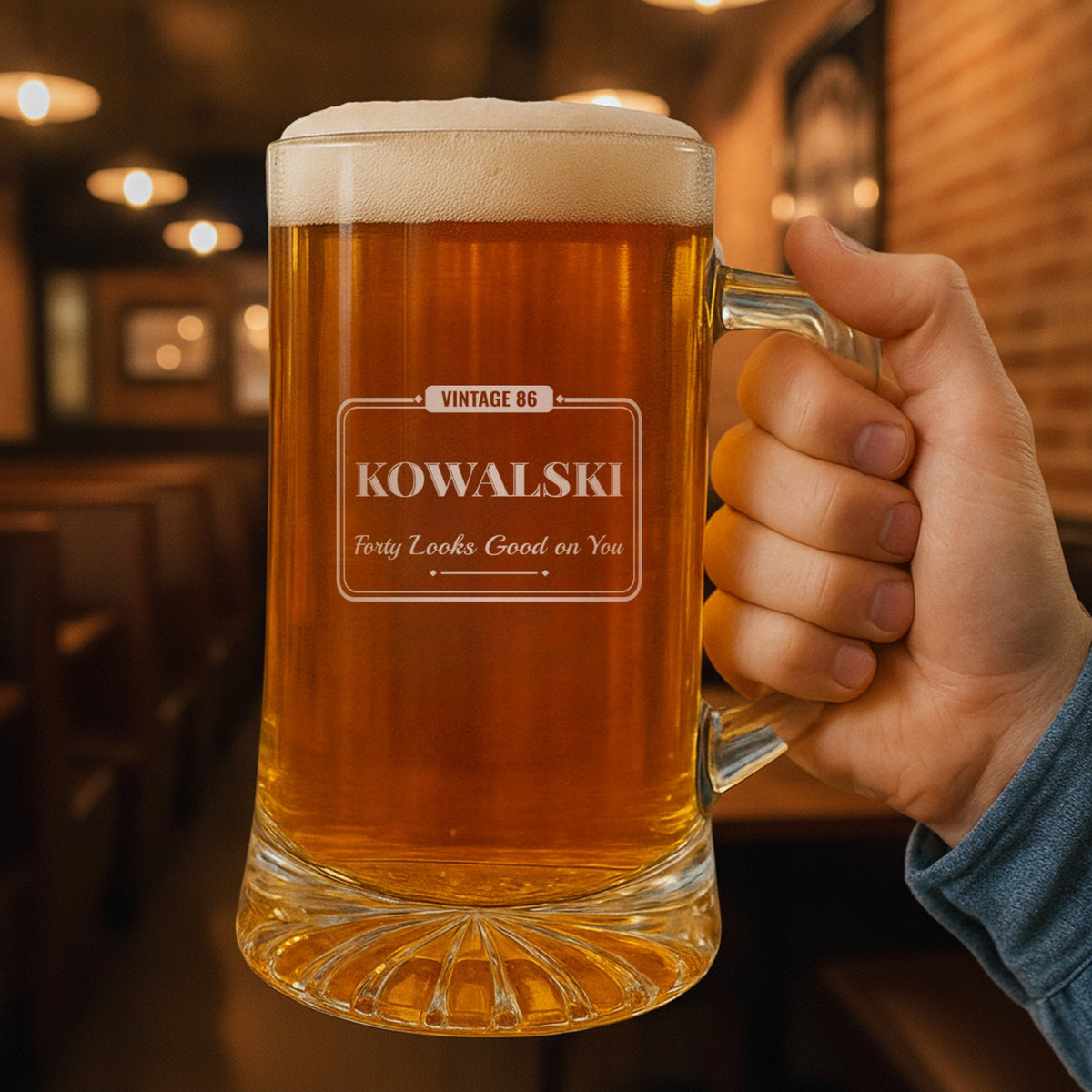 Hand holding a personalized birthday beer stein in a warm pub, engraved Vintage 86, Kowalski and Forty Looks Good on You for a 40th birthday