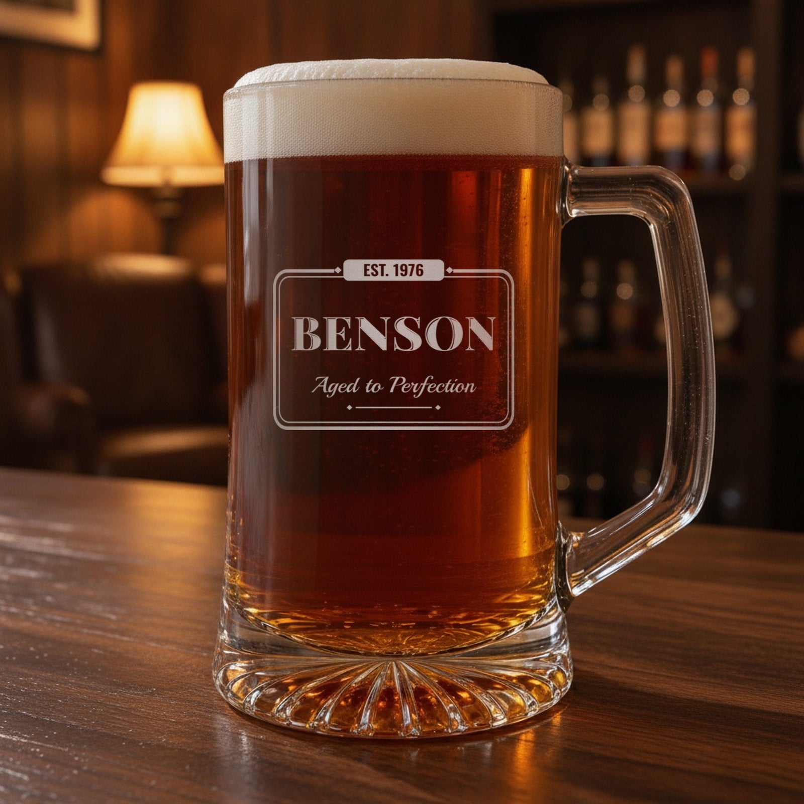Personalized birthday beer stein on a walnut home bar, engraved with EST. 1976, the name Benson and Aged to Perfection in a vintage pub sign frame