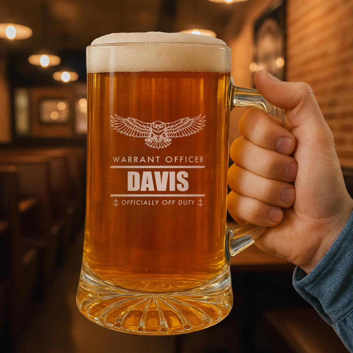 Hand holding a 25 oz personalized Navy retirement beer stein in a pub, engraved with an eagle, Warrant Officer, Davis and Officially Off Duty
