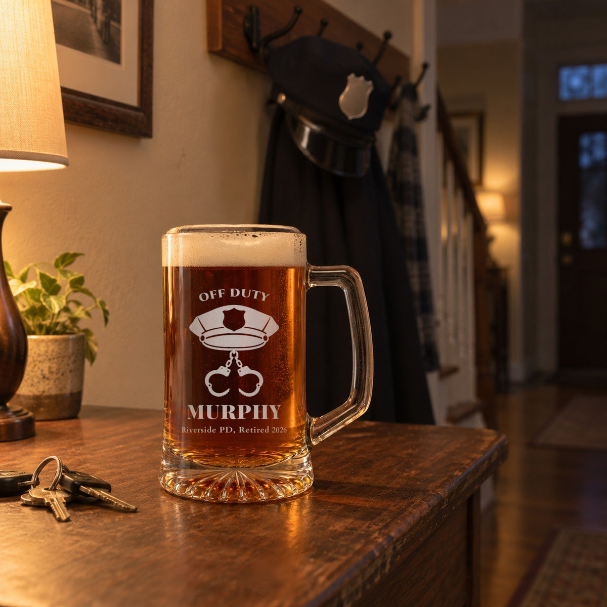 Personalized police retirement beer mug on an entry table at home with a patrol cap hung on the coat rack behind it, engraved OFF DUTY and MURPHY