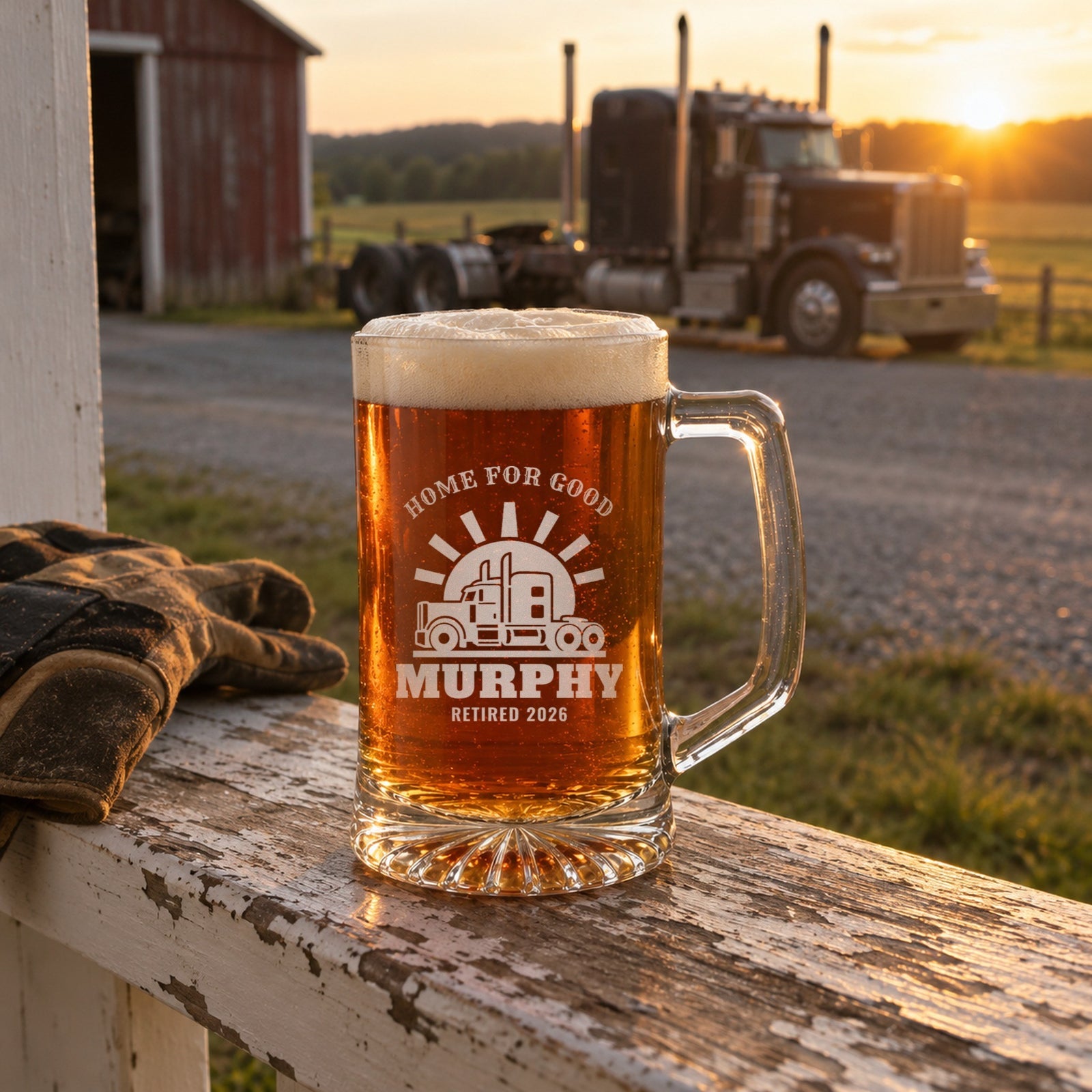 Personalized retired trucker beer stein on a porch railing at sunset with his semi parked by the barn, engraved HOME FOR GOOD, MURPHY and RETIRED 2026