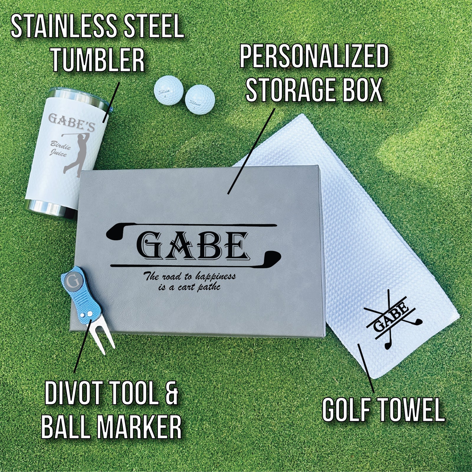 Golf gift set flatlay showing personalized tumbler engraved with sample name "GABE", storage box with matching design, microfiber towel, golf balls, and divot tool with ball marker on green background