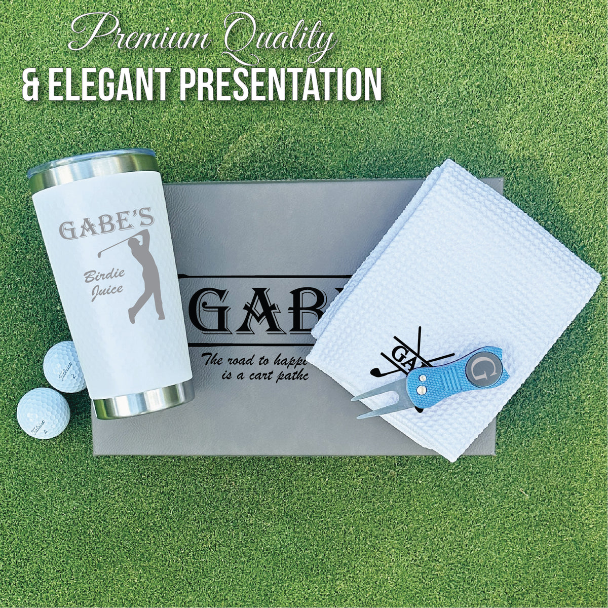 Personalized golf gift set displayed on presentation box showing insulated tumbler engraved with sample name "GABE'S Birdie Juice," embroidered towel with golf club design, divot tool with ball marker, and golf balls on green turf background