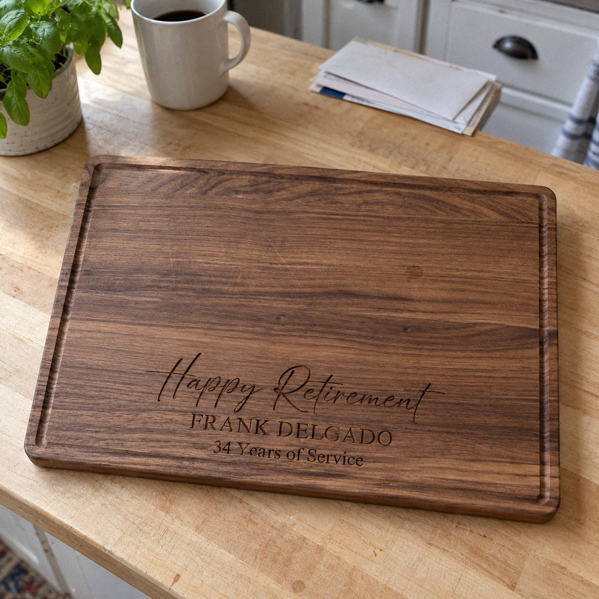 Personalized retirement cutting board in walnut engraved Happy Retirement, FRANK DELGADO and 34 Years of Service, on a butcher-block kitchen counter