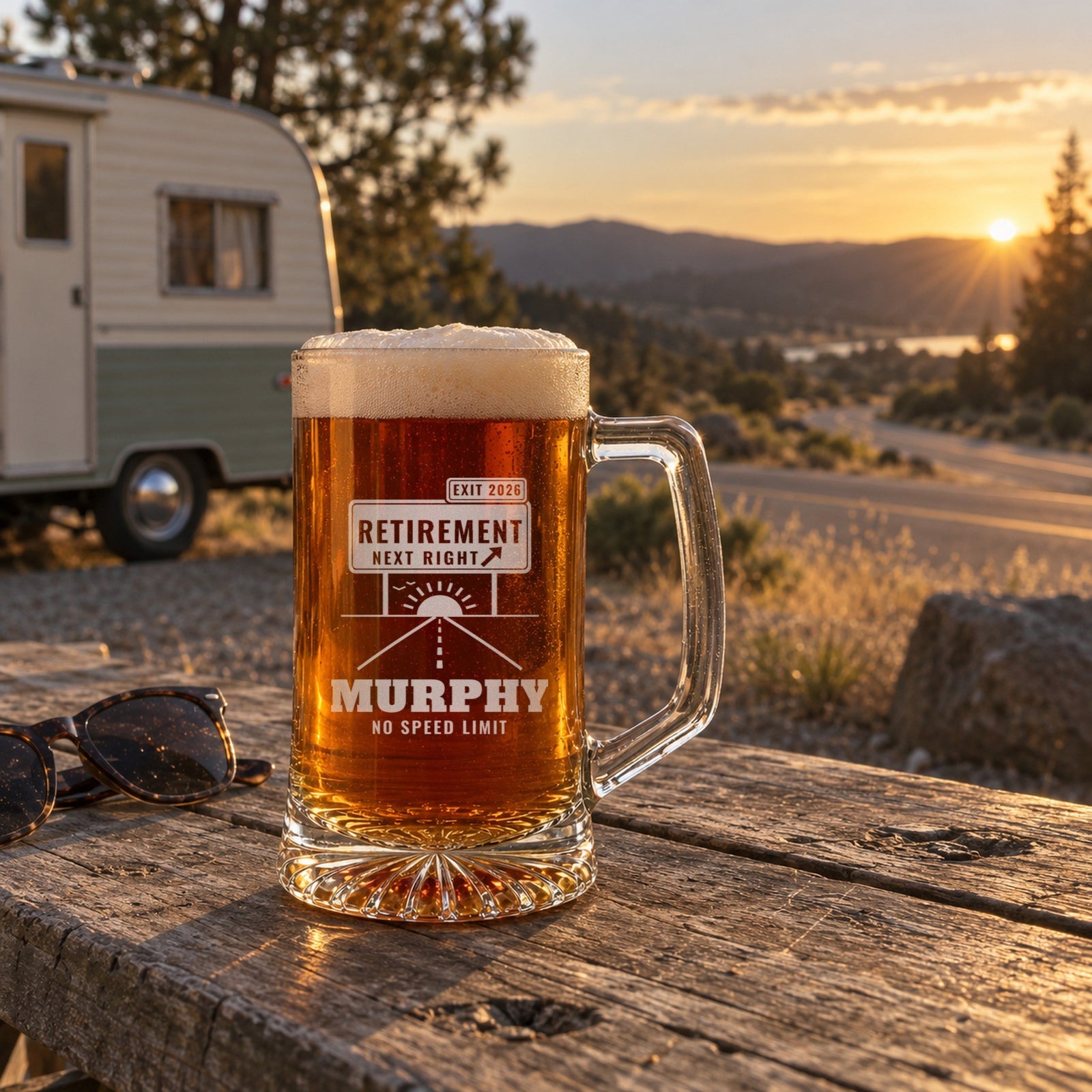 Personalized exit sign retirement beer mug on a campground picnic table at sunset with a vintage camper and a winding road behind it, engraved MURPHY