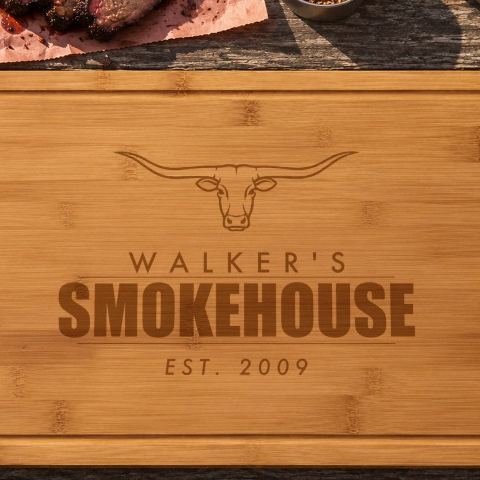 Close-up of the laser engraving on the smokehouse cutting board: the longhorn steer, WALKER'S and SMOKEHOUSE burned into the bamboo grain