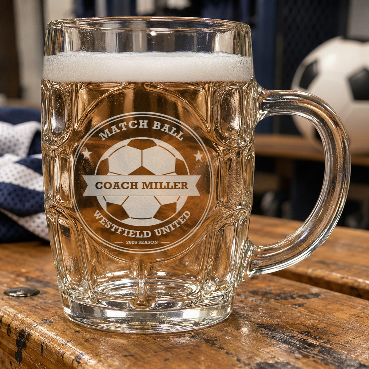 Personalized soccer coach beer mug beside a soccer ball and a folded jersey, frosted engraving reading Match Ball, Coach Miller and Westfield United