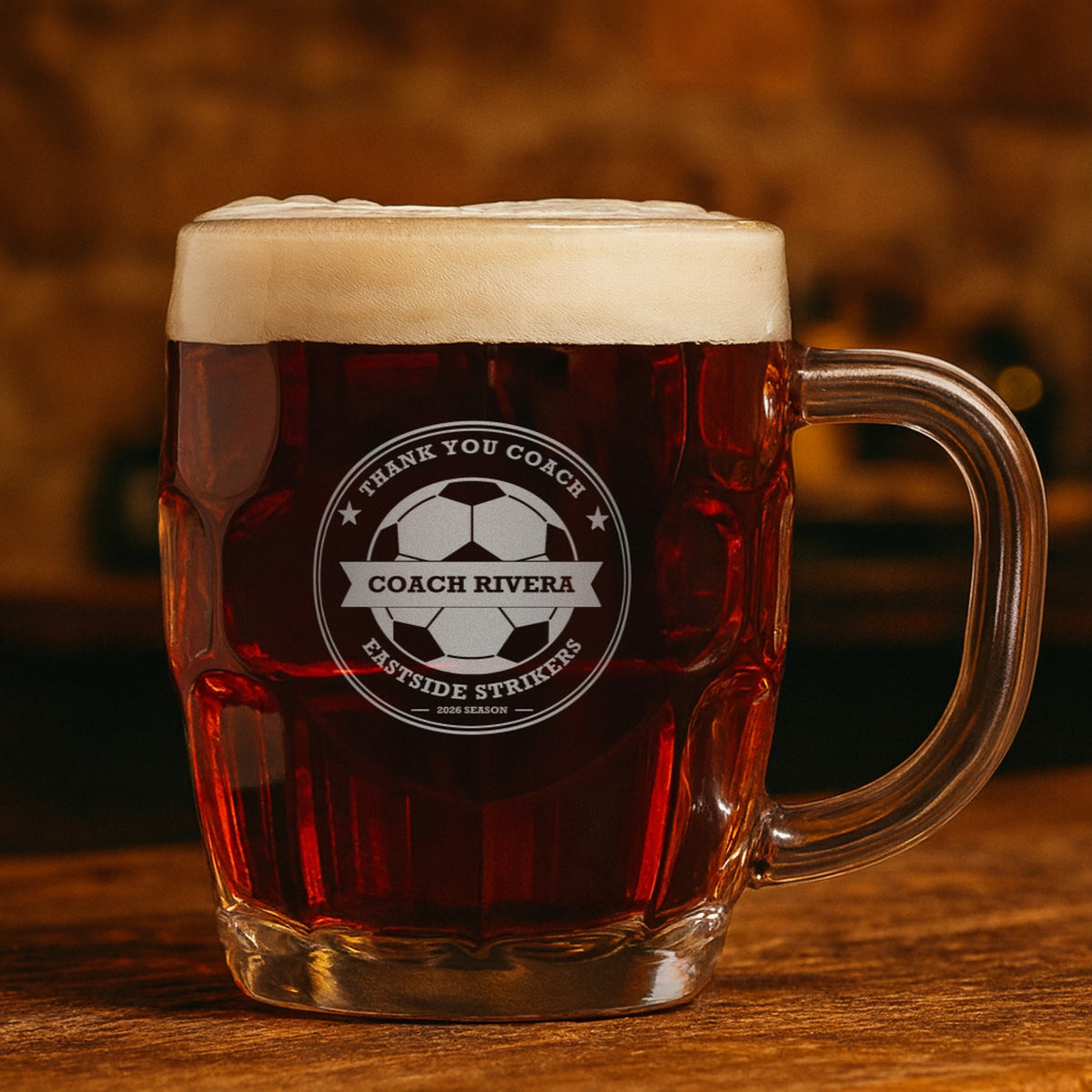 Engraved soccer coach mug with dark amber ale reading Thank You Coach, Coach Rivera and Eastside Strikers, showing the top line can be changed
