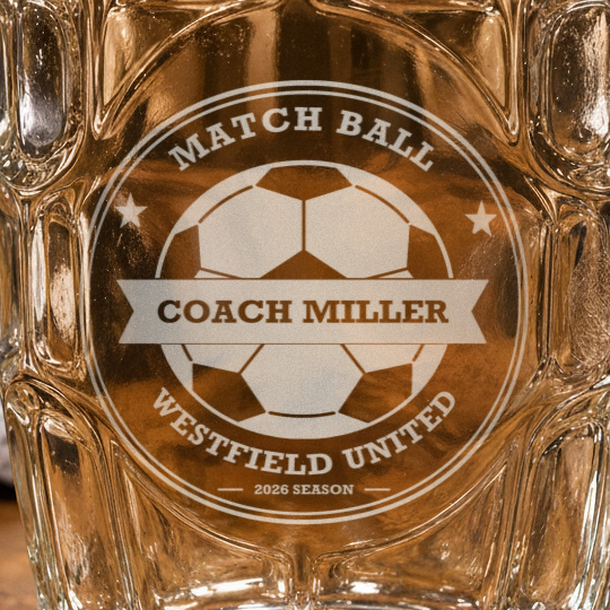Close-up of the frosted laser engraving on the soccer coach mug, showing the soccer crest, the Coach Miller banner and the team name arc