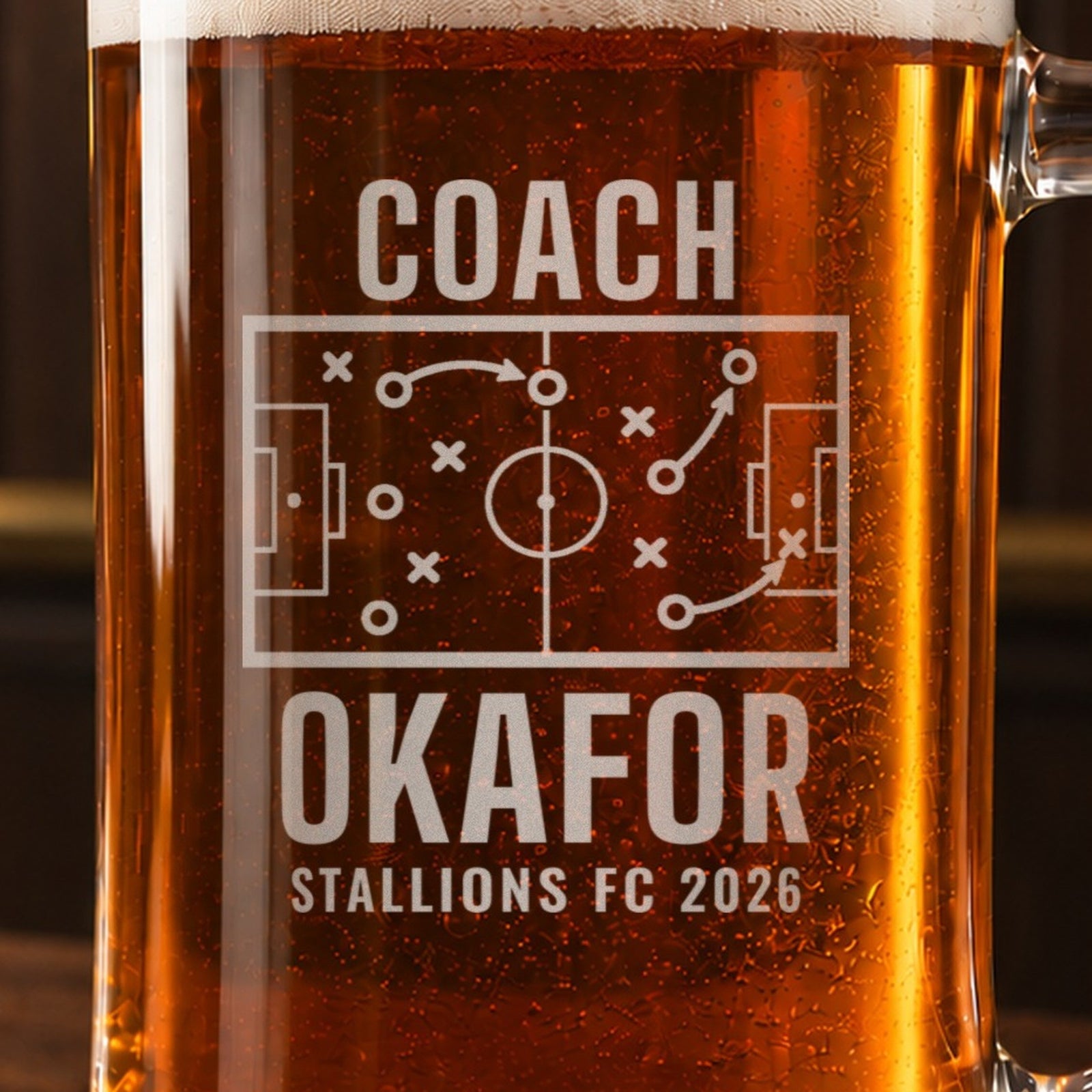 Close-up of the frosted engraving on the soccer coach tactics board beer stein, a soccer pitch tactics board with X's, O's and passing arrows: Coach, Okafor, Stallions FC 2026
