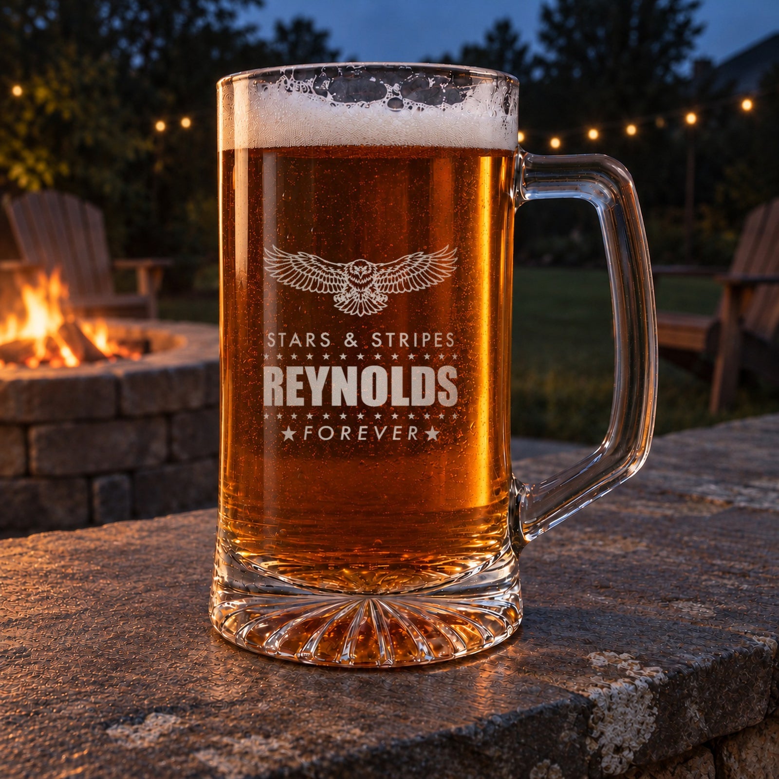 Engraved eagle beer stein on a stone patio wall by a backyard fire pit at dusk, personalized Stars and Stripes, Reynolds and Forever