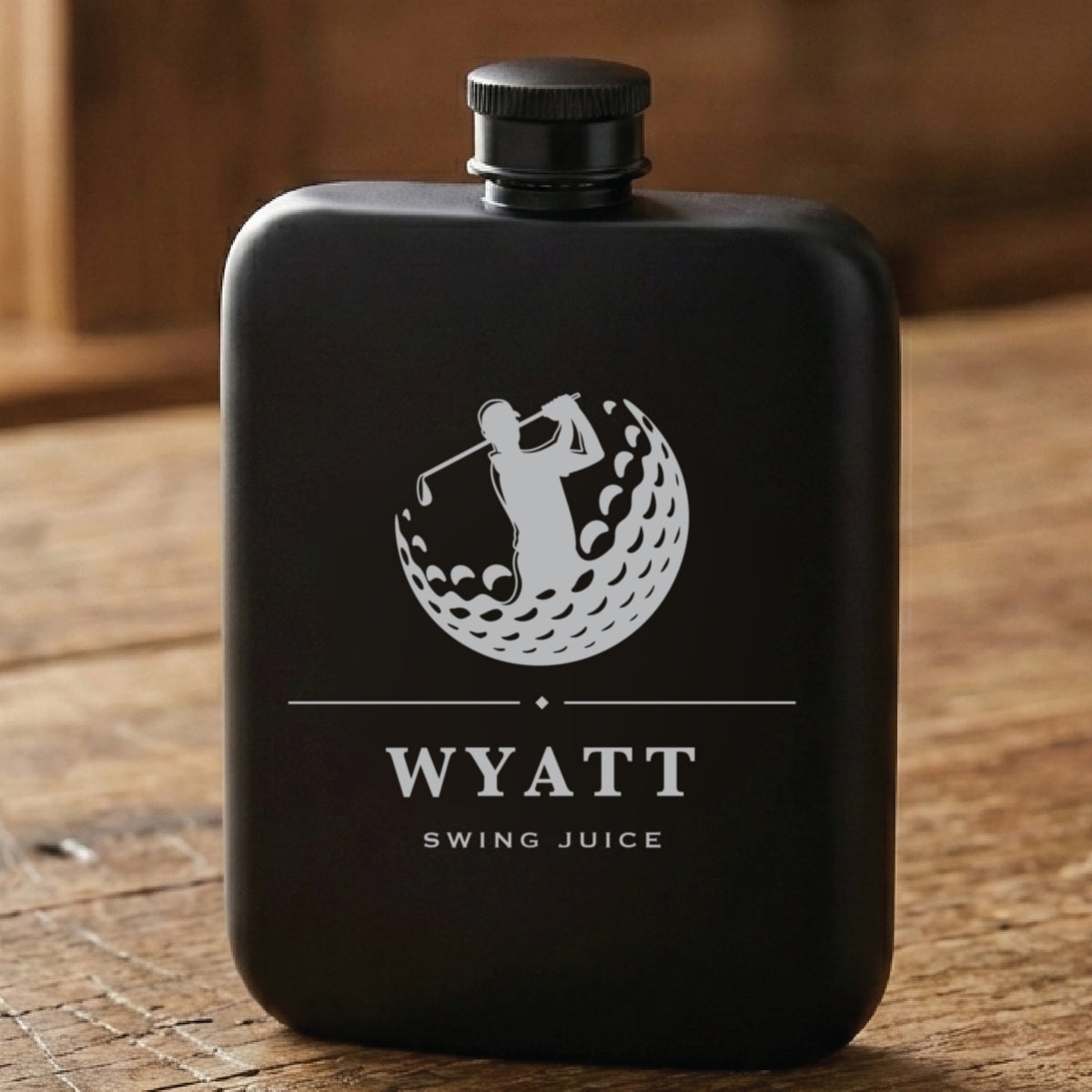 Matte black personalized golf flask laser engraved with a golfer mid swing inside a golf ball, the name Wyatt and Swing Juice.