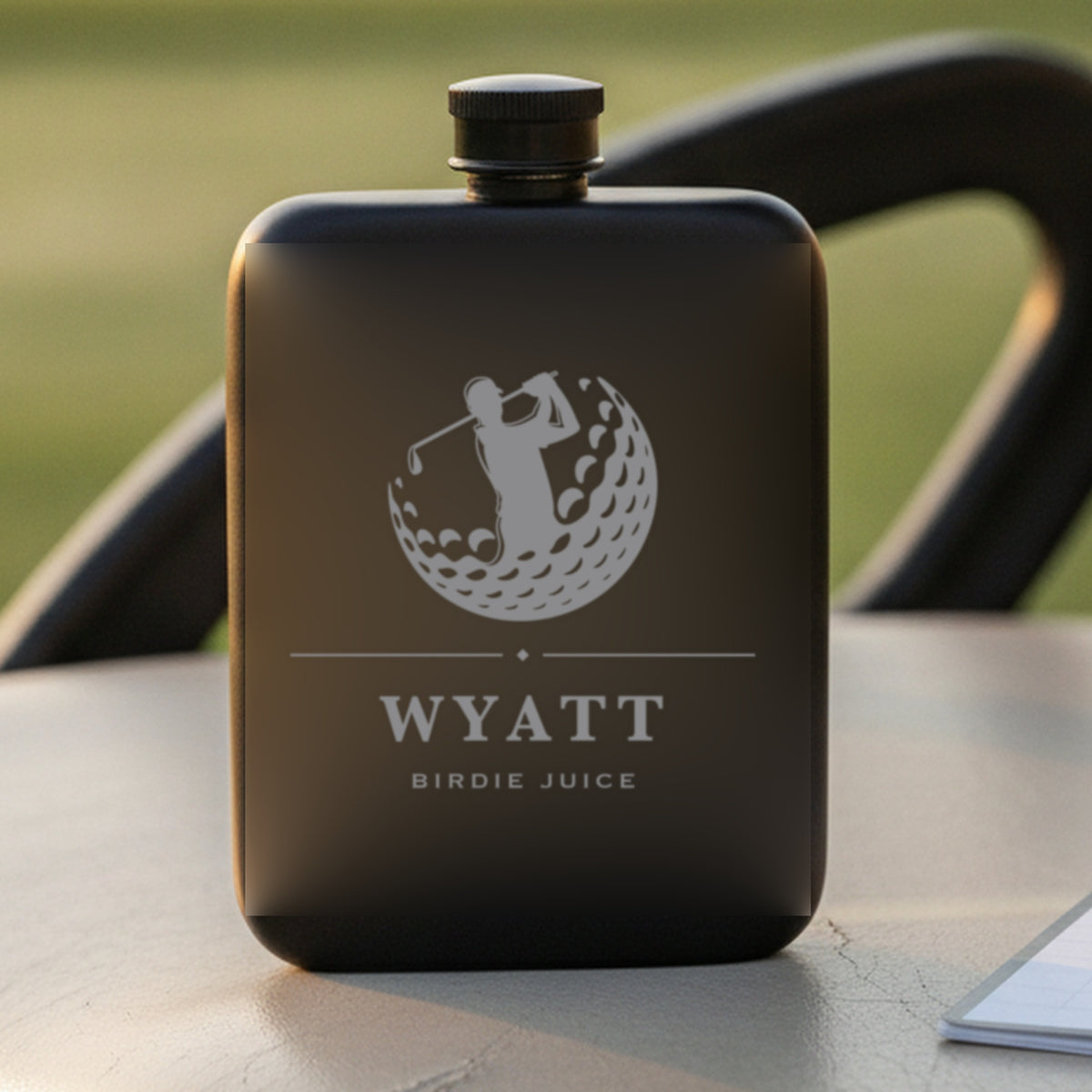 Personalized golf flask reading Birdie Juice standing on a golf cart seat beside a scorecard with a sunlit fairway behind.