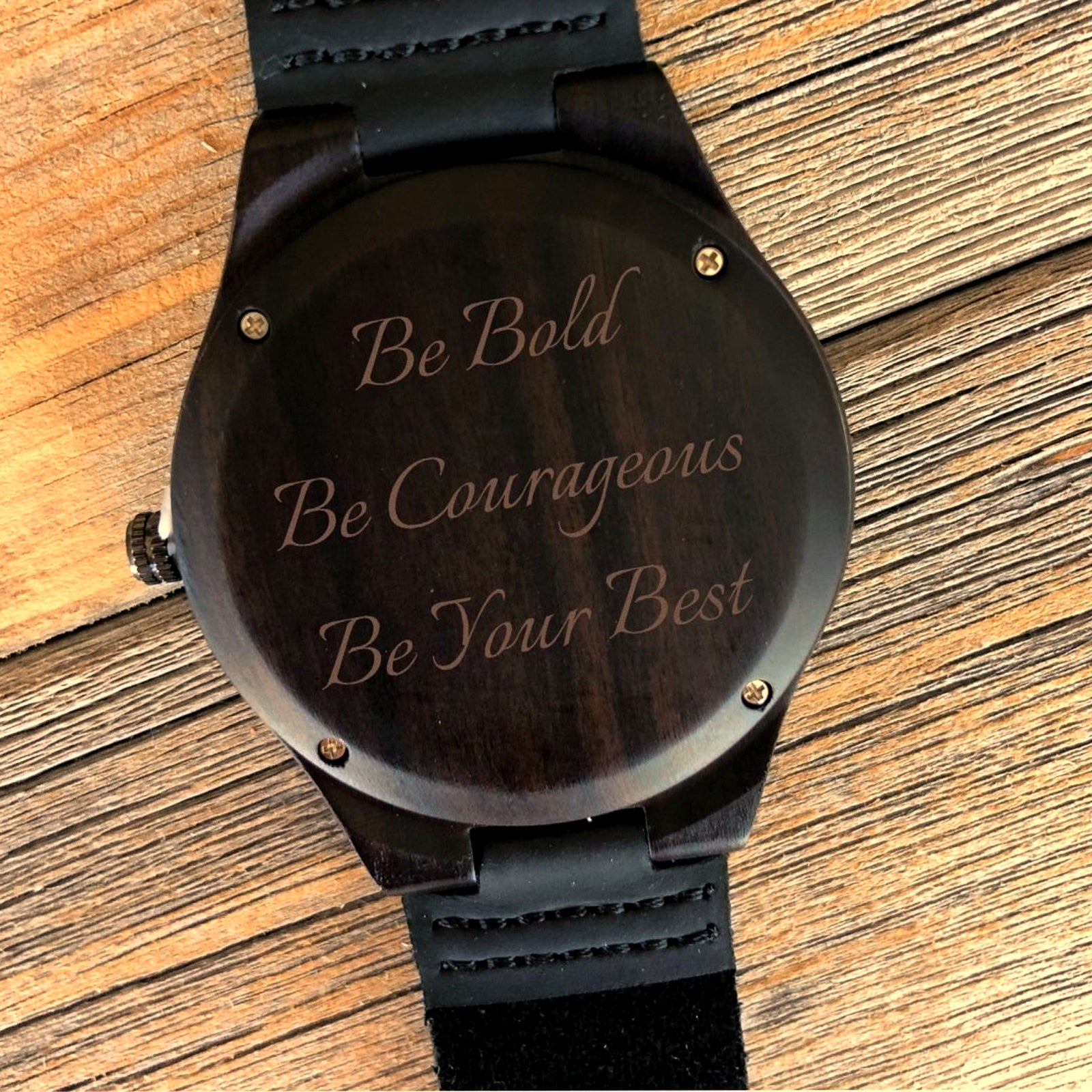Custom engraved wood watch in dark ebony sandalwood with a black leather strap, caseback laser engraved with a personalized three line message