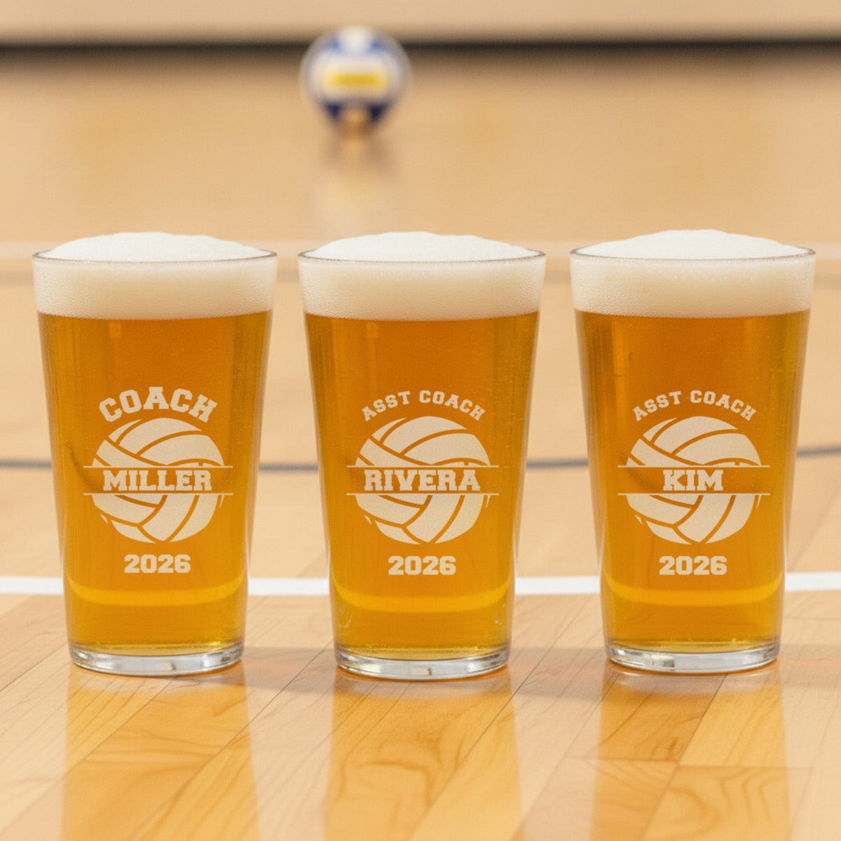 Three volleyball coach pint glasses in a row engraved for the head coach Miller and assistant coaches Rivera and Kim, one glass per coach