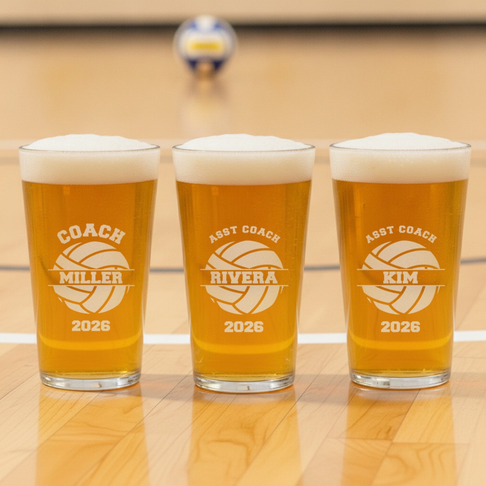 Three volleyball coach pint glasses in a row engraved for the head coach Miller and assistant coaches Rivera and Kim, one glass per coach