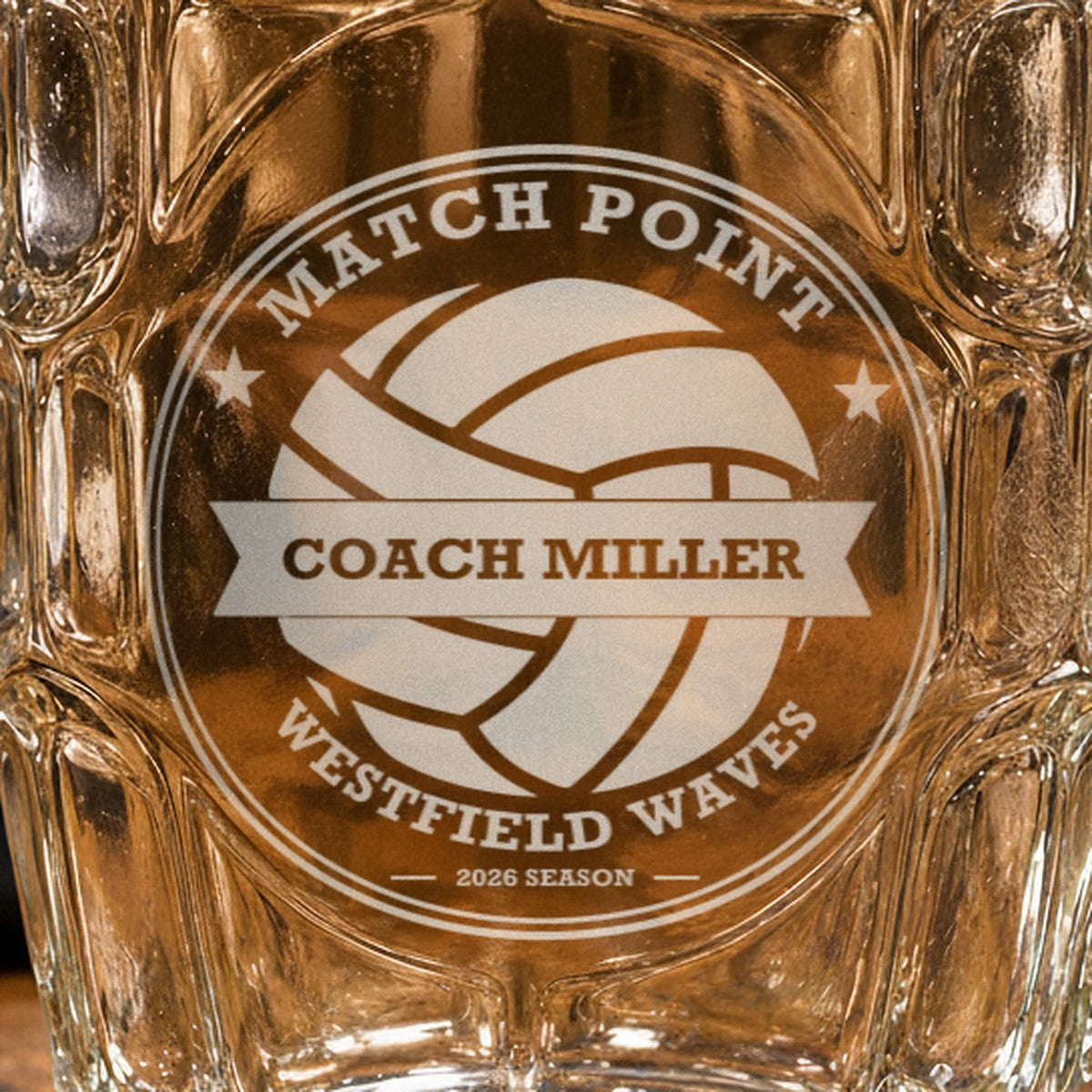 Close-up of the frosted laser engraving on the volleyball coach stein, showing the volleyball crest, the Coach Miller banner and the team name arc