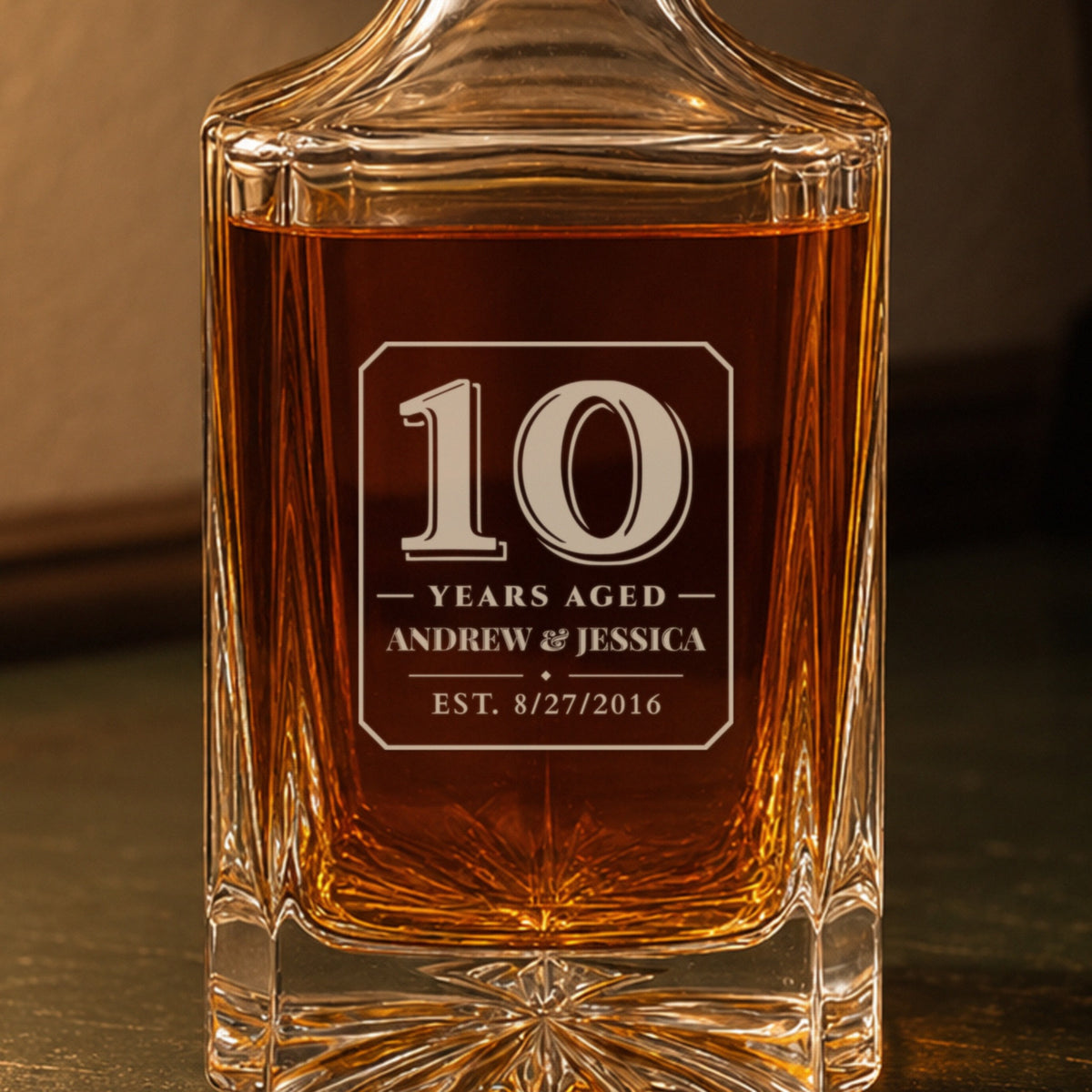Close-up of the frosted engraving: a bold 10, Years Aged, Andrew & Jessica, est. 8/27/2016, on a personalized 10th anniversary decanter