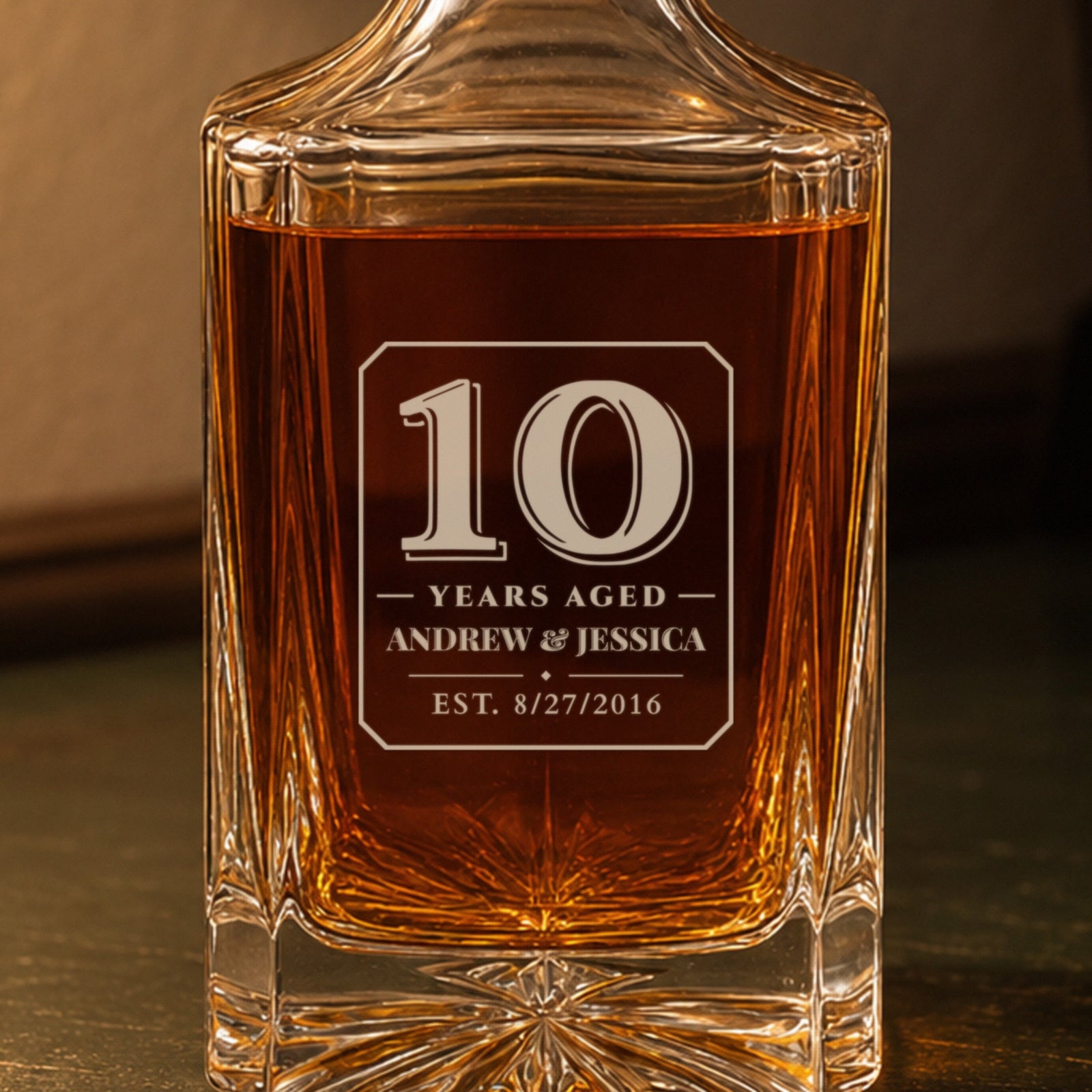 Close-up of the frosted engraving: a bold 10, Years Aged, Andrew & Jessica, est. 8/27/2016, on a personalized 10th anniversary decanter