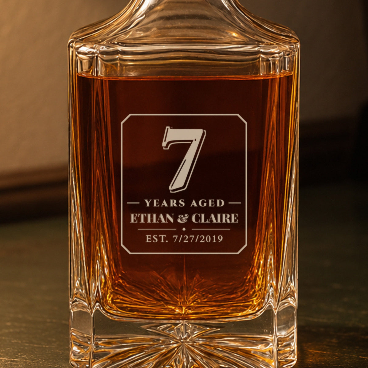 Close-up of the frosted engraving: a bold 7, Years Aged, Ethan & Claire, est. 7/27/2019, on a personalized 7th anniversary decanter