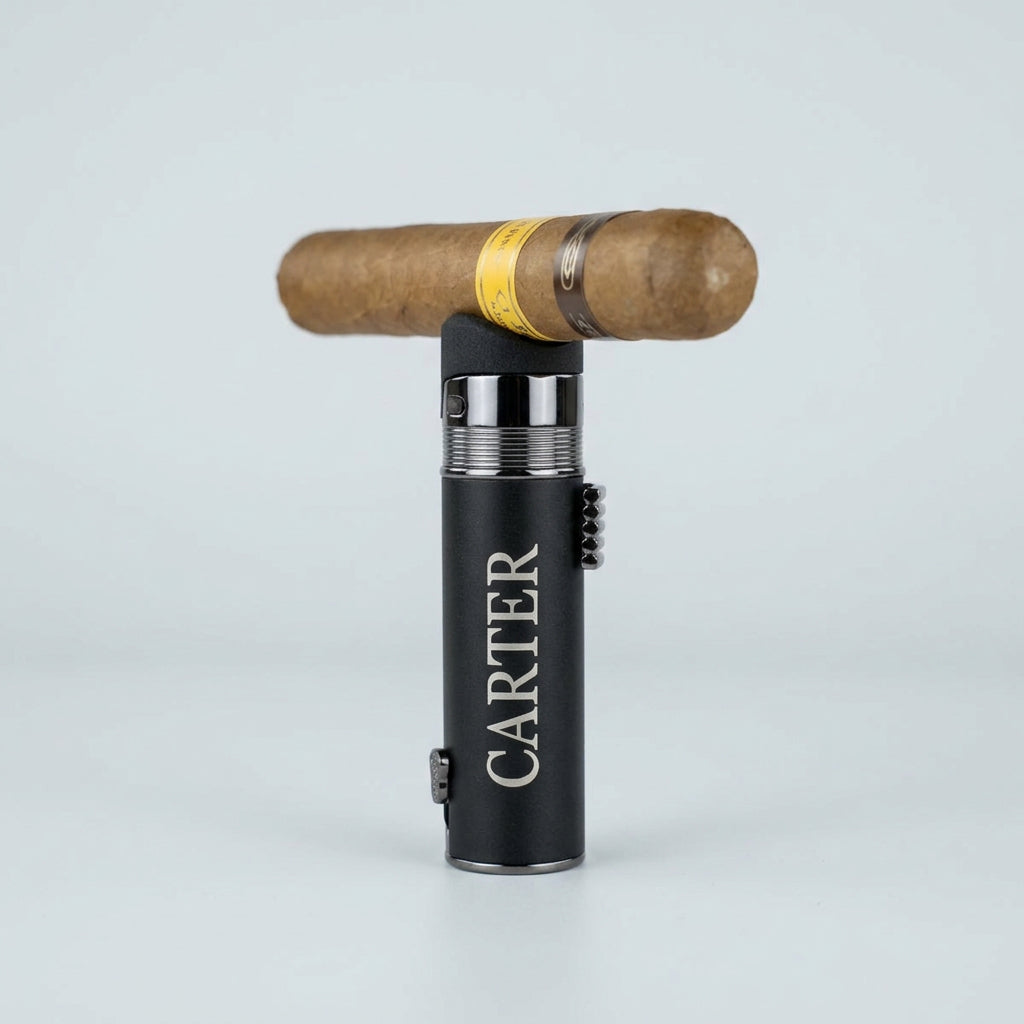Personalized cigar lighter engraved CARTER standing upright with a cigar resting on its built-in cigar rest, beside a bourbon bottle on a rustic wood table